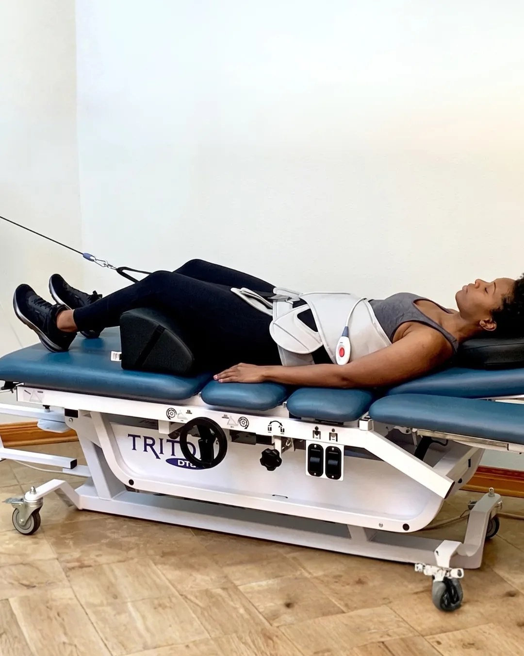 A patient lying face up on a decompression table with the traction harness in place
